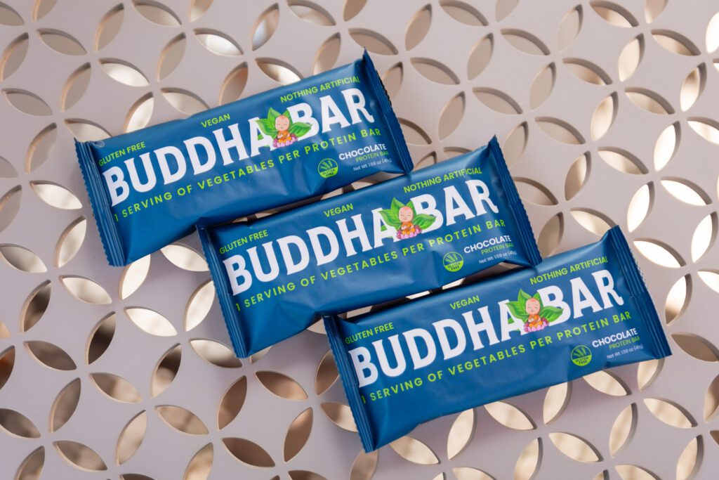 Three blue packages of Buddha Bar chocolate protein bars.